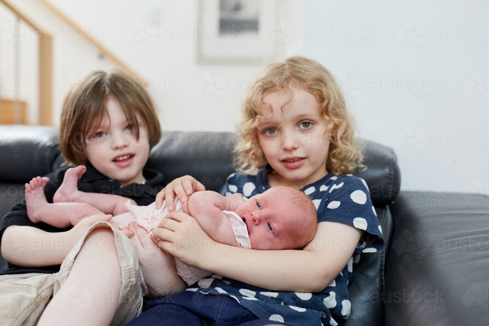 Young boy and girl holding infant - Australian Stock Image