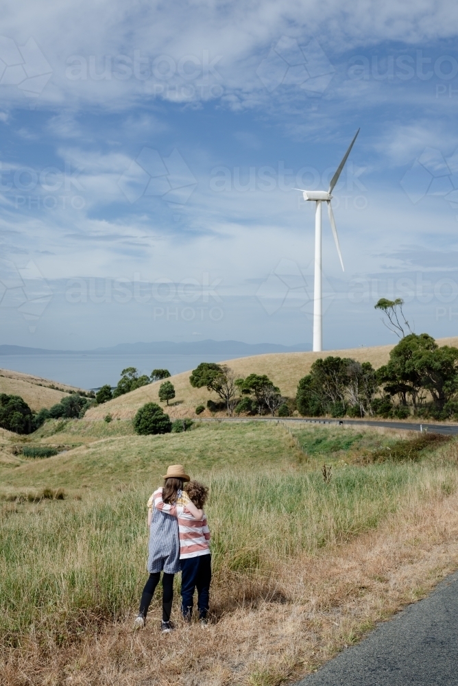 Young boy and girl together in rural Gippsland near Toora, with a wind turbine in the distance - Australian Stock Image