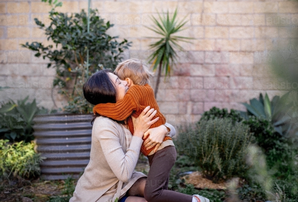 Young boy and mother hugging in home garden - Australian Stock Image