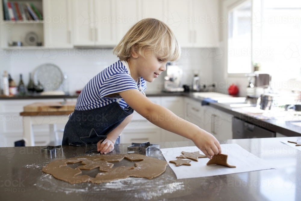 Young boy baking gingerbread biscuits in kitchen at home - Australian Stock Image