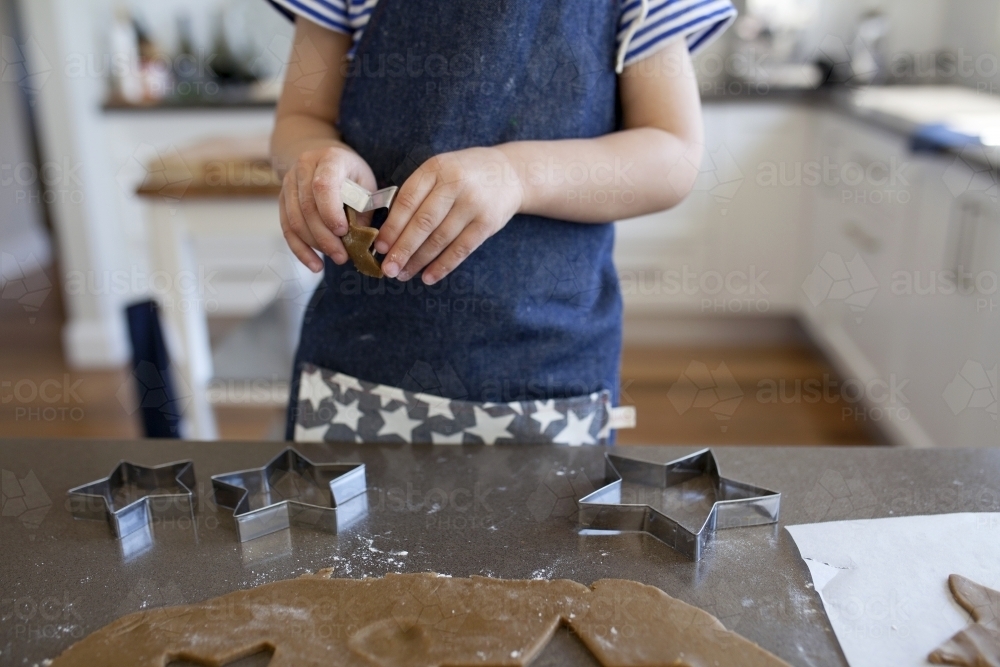 Young boy baking gingerbread biscuits in kitchen at home - Australian Stock Image
