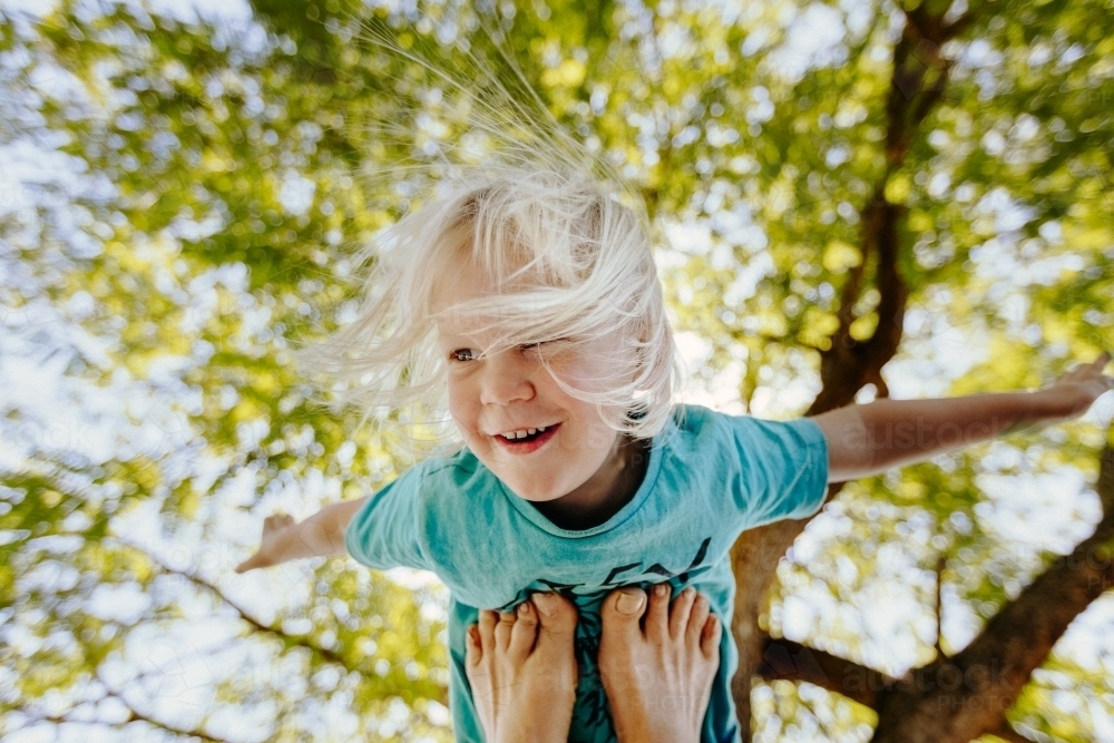 Young boy being held up in the air on feet - Australian Stock Image