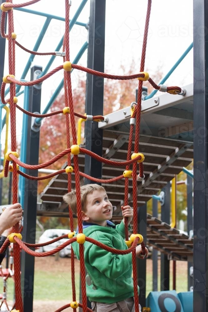 Young boy climbing on play equipment at the park - Australian Stock Image