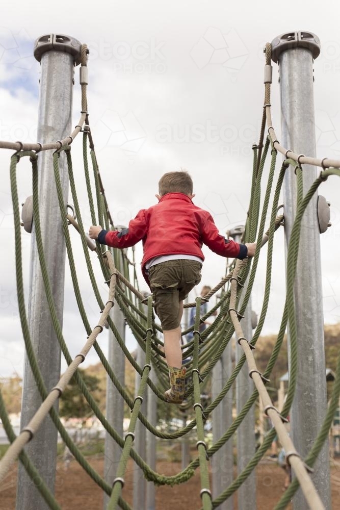 Young boy climbing playground equipment at park - Australian Stock Image