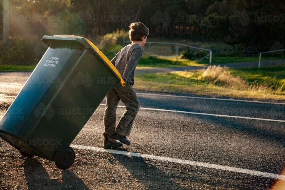 Young boy doing job taking bin across the road - Australian Stock Image