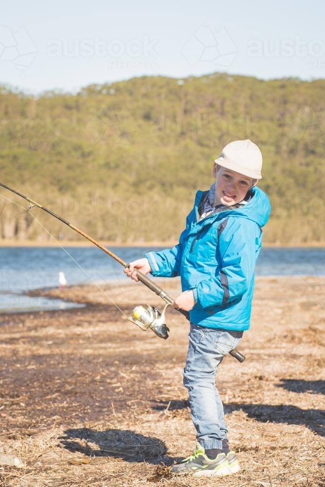 Young boy fishing on the banks of a river - Australian Stock Image