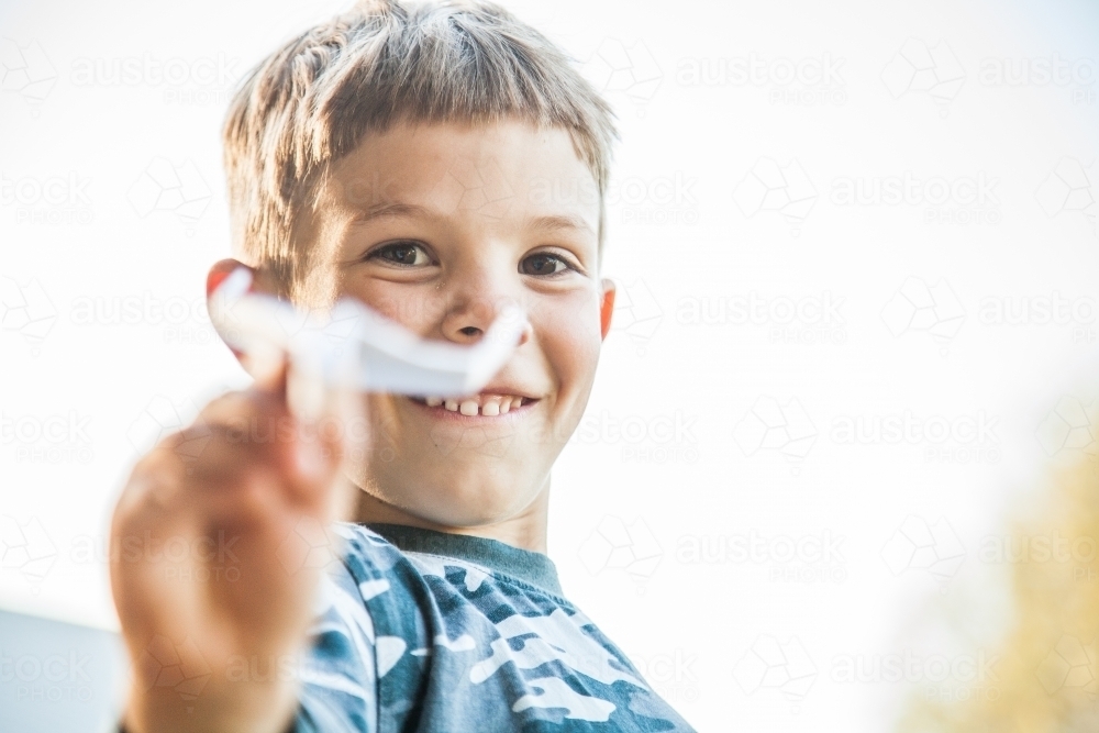 Young boy flying a paper plane in the backyard - Australian Stock Image
