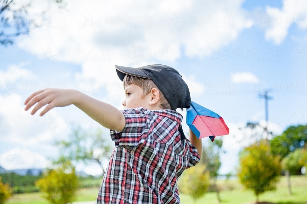 Young boy flying a paper plane outside - Australian Stock Image