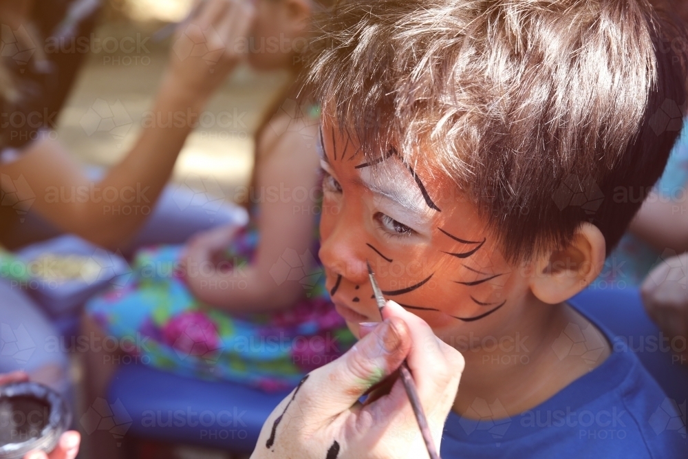 Young boy getting face painted as a tiger - Australian Stock Image
