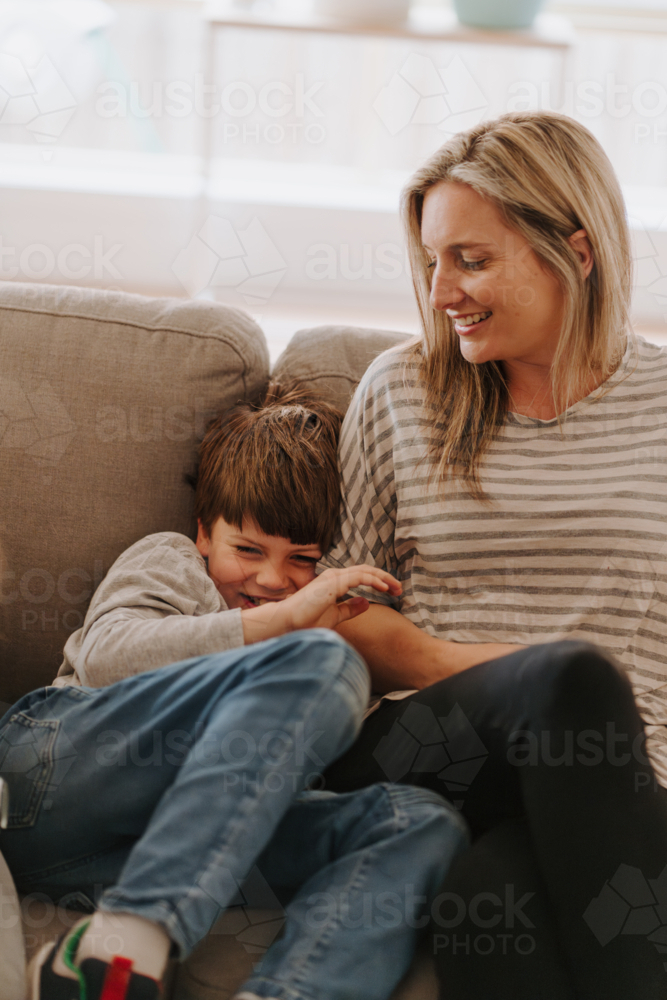 Young boy giggling while snuggling into mums side. - Australian Stock Image