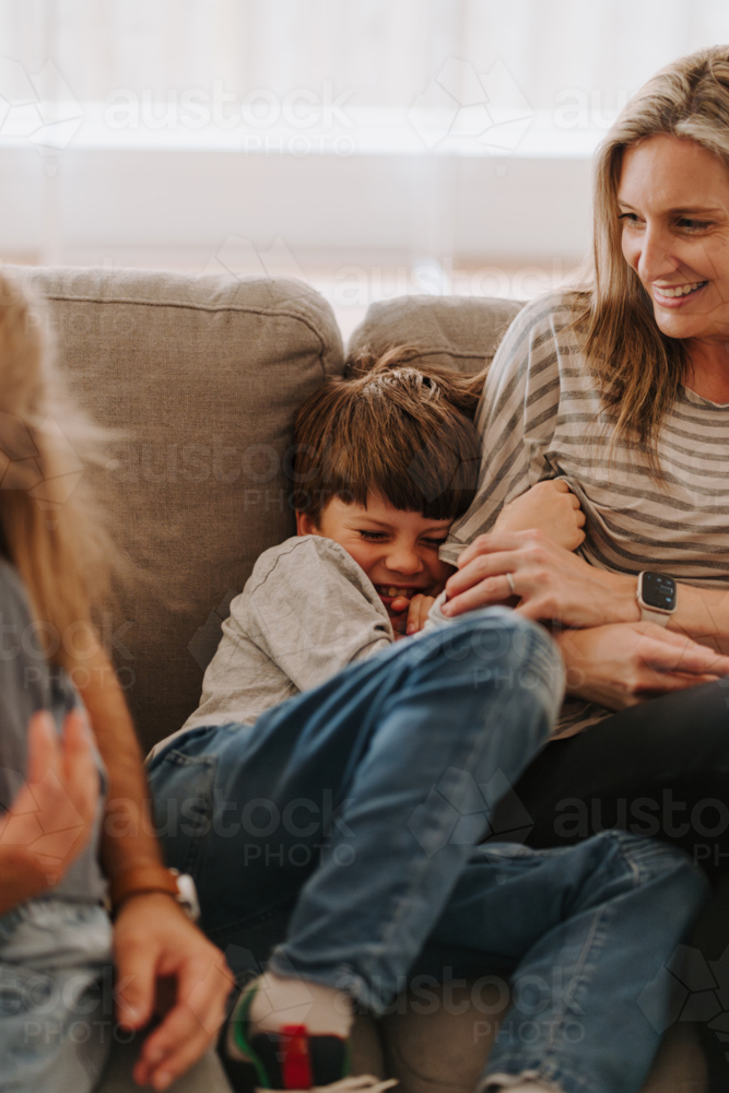 Young boy giggling while snuggling into mums side. - Australian Stock Image