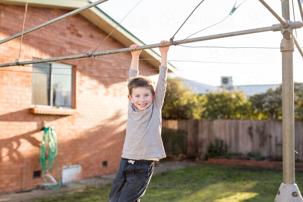 Young boy hanging from washing line - Australian Stock Image