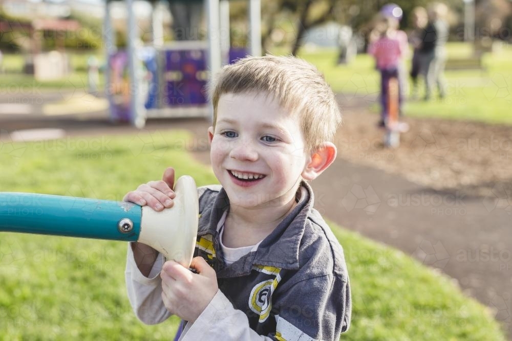 Young boy happily playing at the park - Australian Stock Image