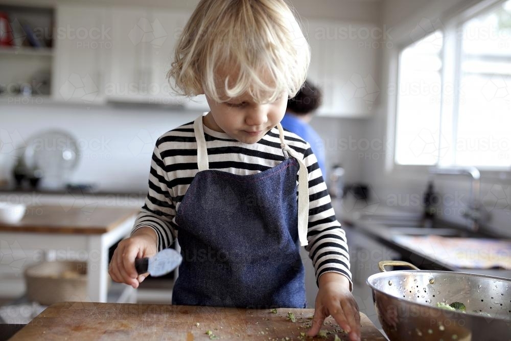 Young boy helping chop vegetables - Australian Stock Image