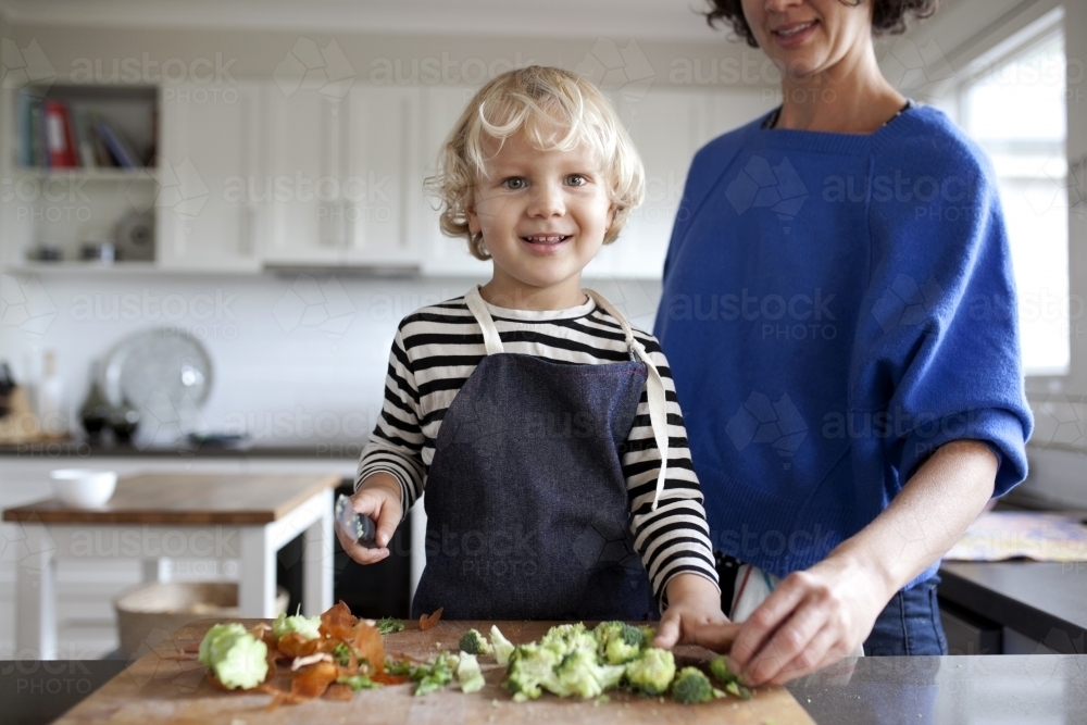 Young boy helping chop vegetables with mum - Australian Stock Image
