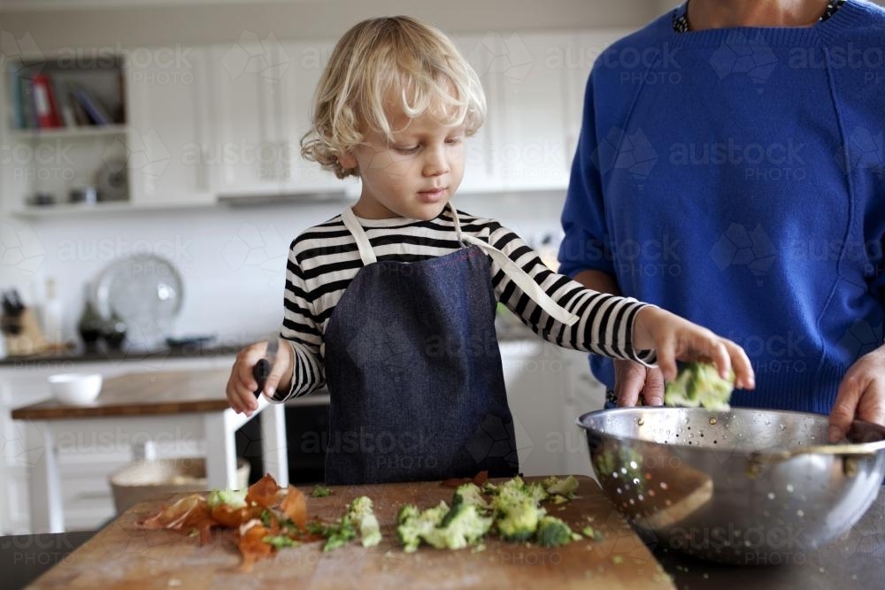 Young boy helping prepare vegetables for dinner - Australian Stock Image