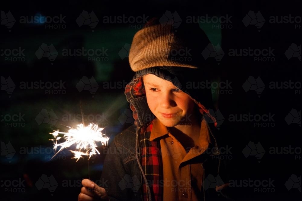 Young boy holding a burning sparkler on a bonfire night - Australian Stock Image