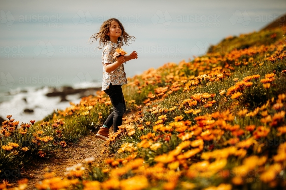 Young boy holding flowers in a field of flowers - Australian Stock Image