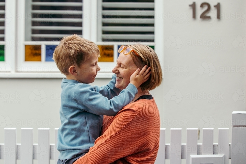 Young boy holds his mother's face in his hands - Australian Stock Image