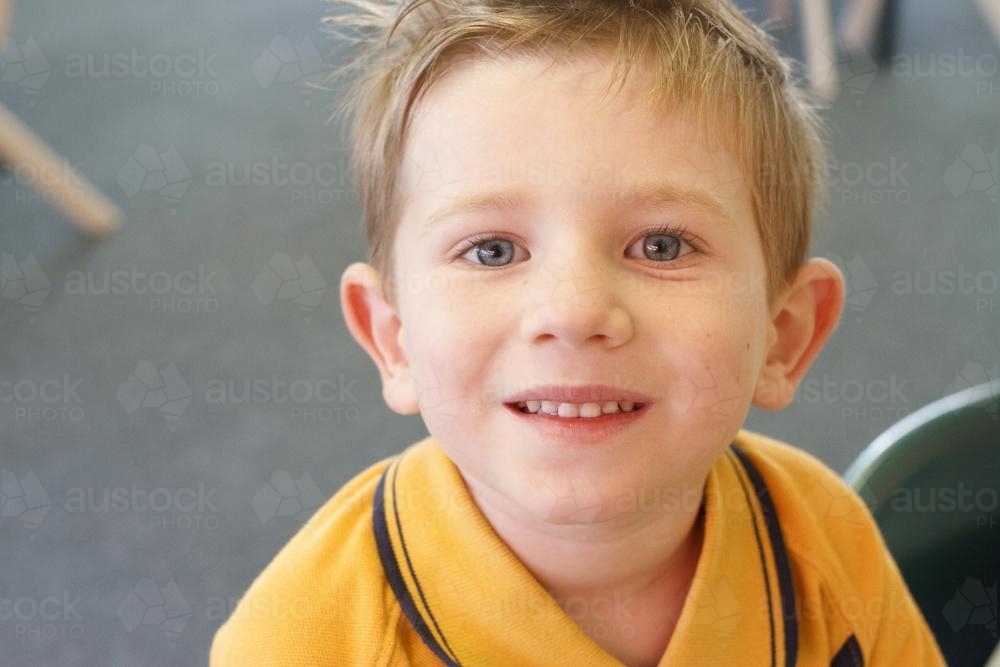 Young boy in school uniform smiling up at camera - Australian Stock Image