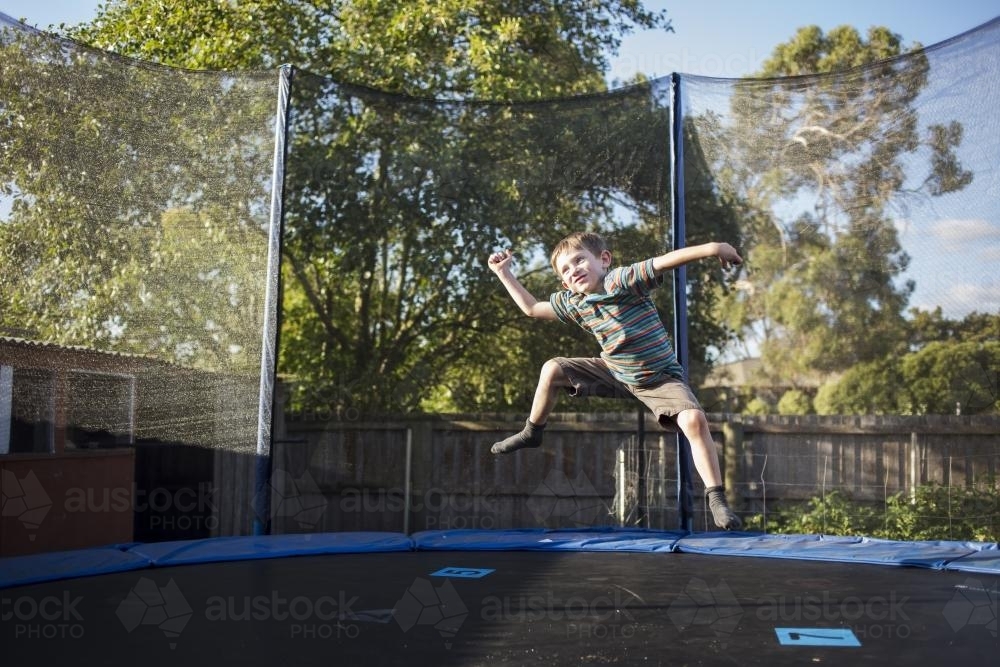 Young boy jumping on trampoline - Australian Stock Image