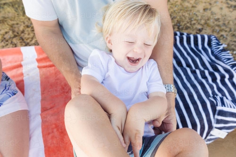 Young boy laughing as dad tickles him - Australian Stock Image