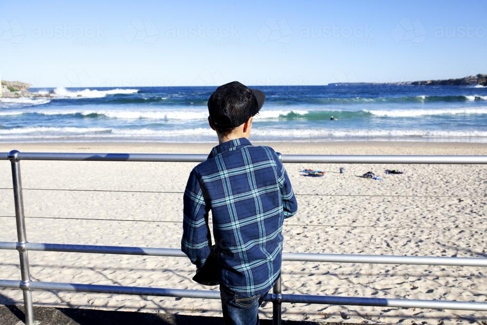 Young boy looking out at the ocean on a bright day - Australian Stock Image