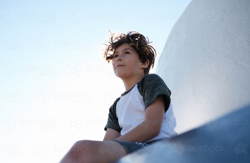 Young boy looking out to a view whilst seated - Australian Stock Image