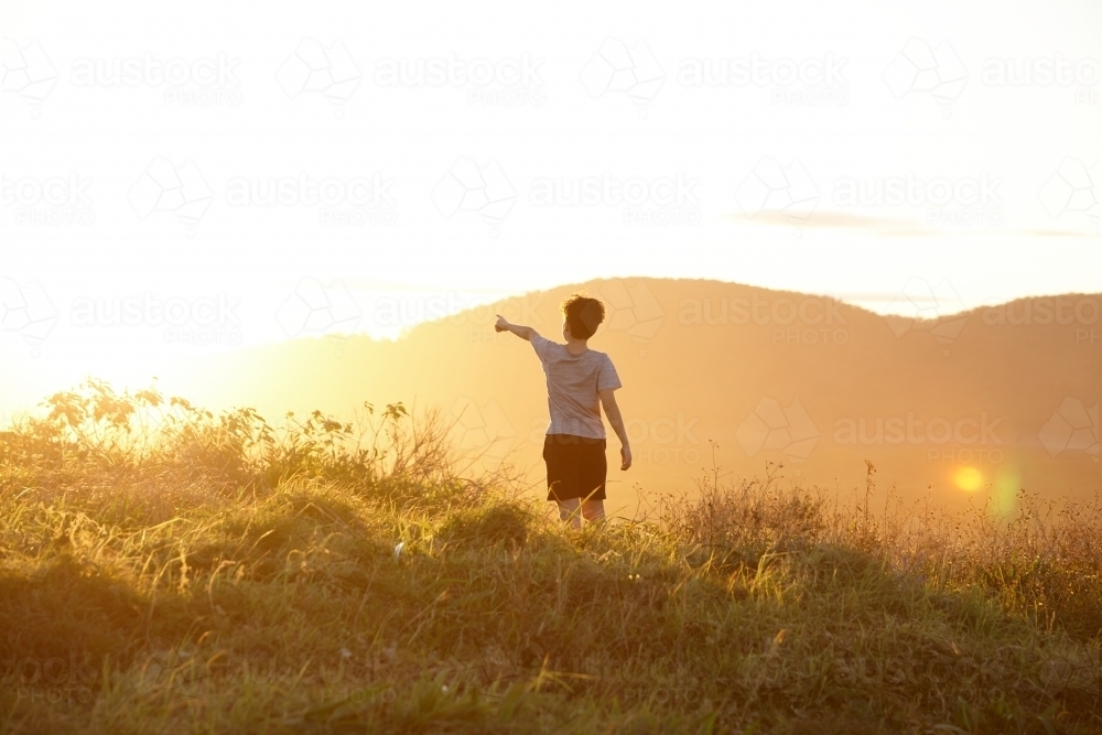 Young boy looking out to mountains at sunset - Australian Stock Image