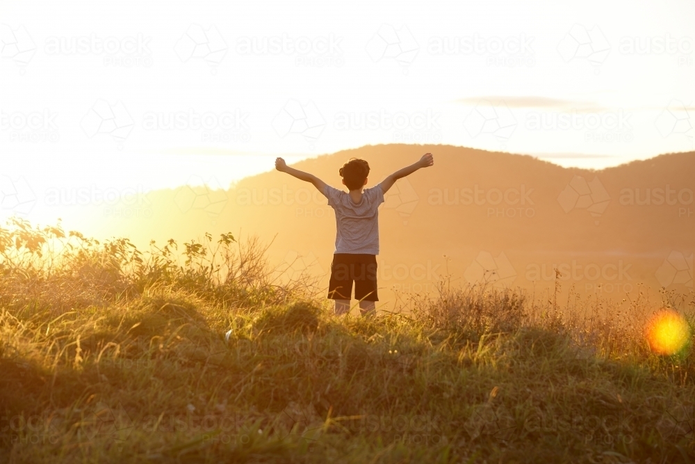 Young boy looking out to mountains at sunset - Australian Stock Image