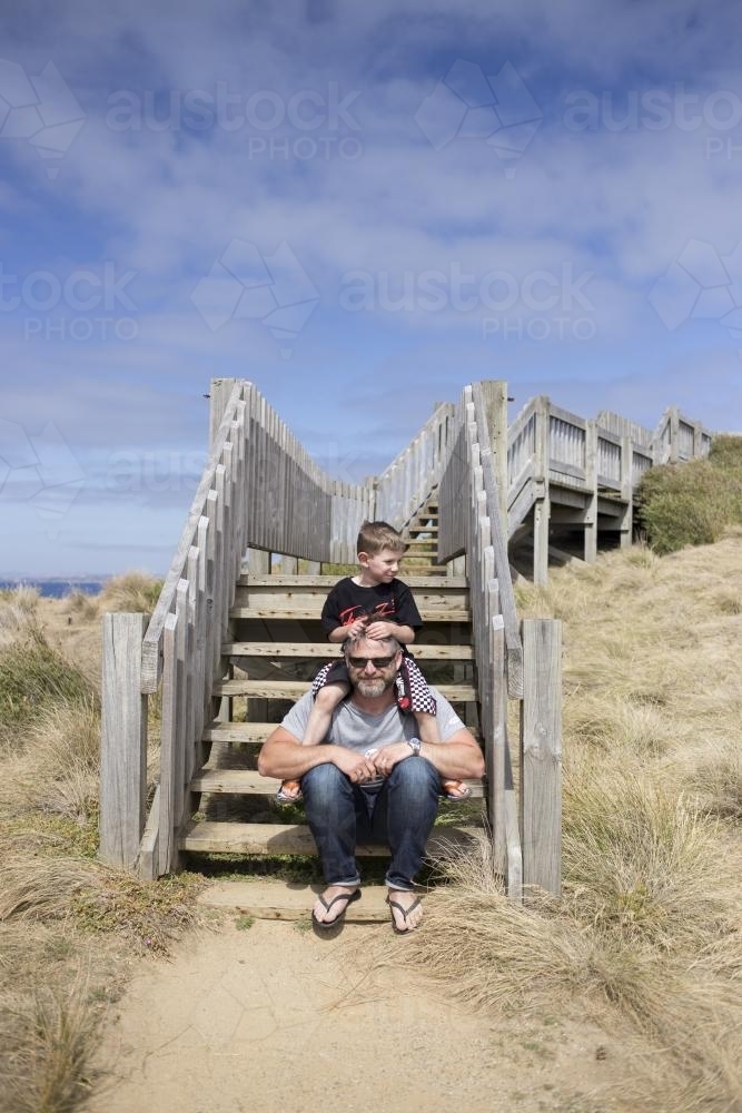 Young boy on Father's shoulders at the beach - Australian Stock Image