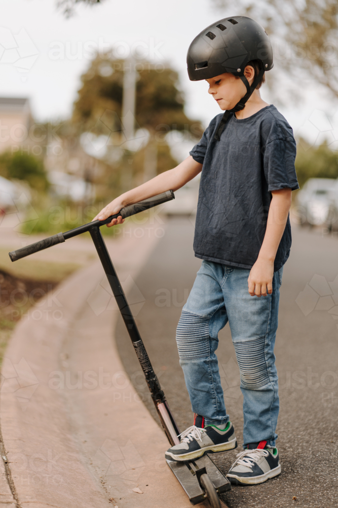 Young boy on his scooter on the street. - Australian Stock Image