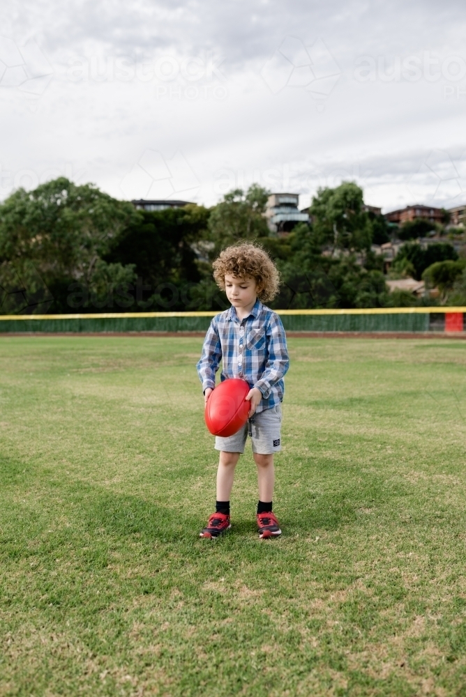 Young boy playing AFL at the park oval - Australian Stock Image