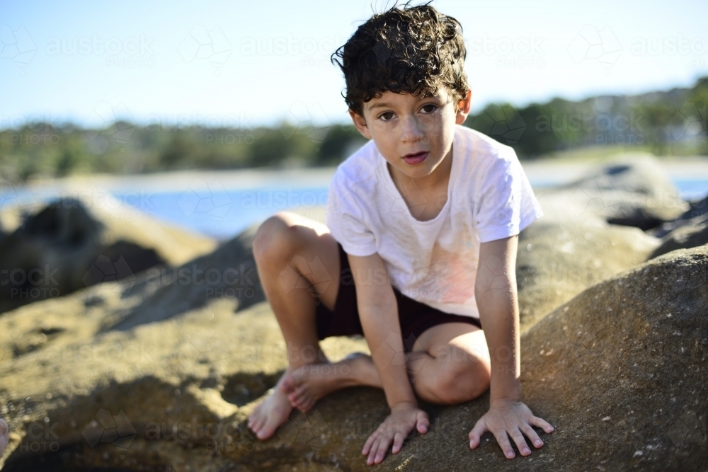 Young boy playing at beach rockpools - Australian Stock Image