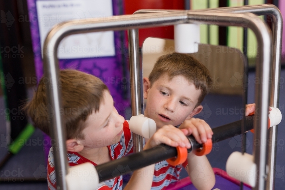 Young boy playing game looking into mirror at museum - Australian Stock Image