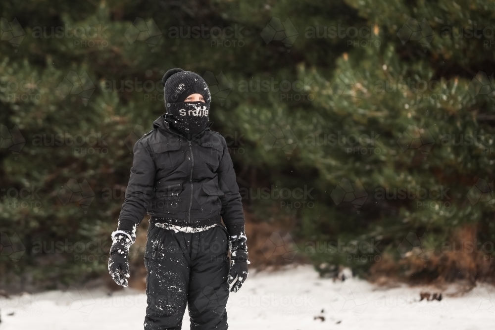 Young boy playing in snowy winter wonderland wearing snow suit - Australian Stock Image