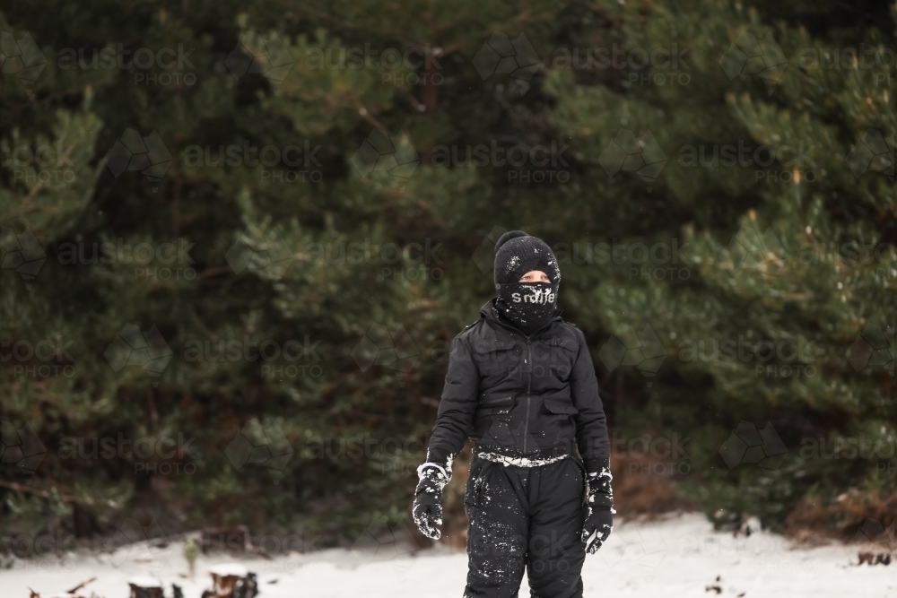 Young boy playing in snowy winter wonderland wearing snow suit - Australian Stock Image