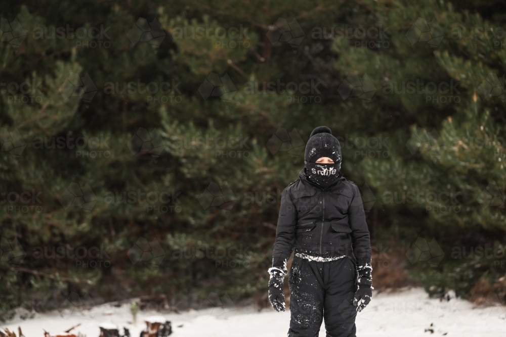 Young boy playing in snowy winter wonderland wearing snow suit - Australian Stock Image