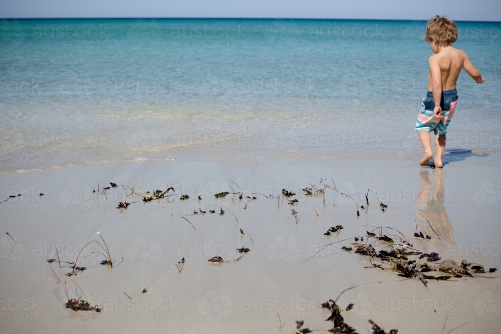 Young boy playing in the waters edge at the beach - Australian Stock Image