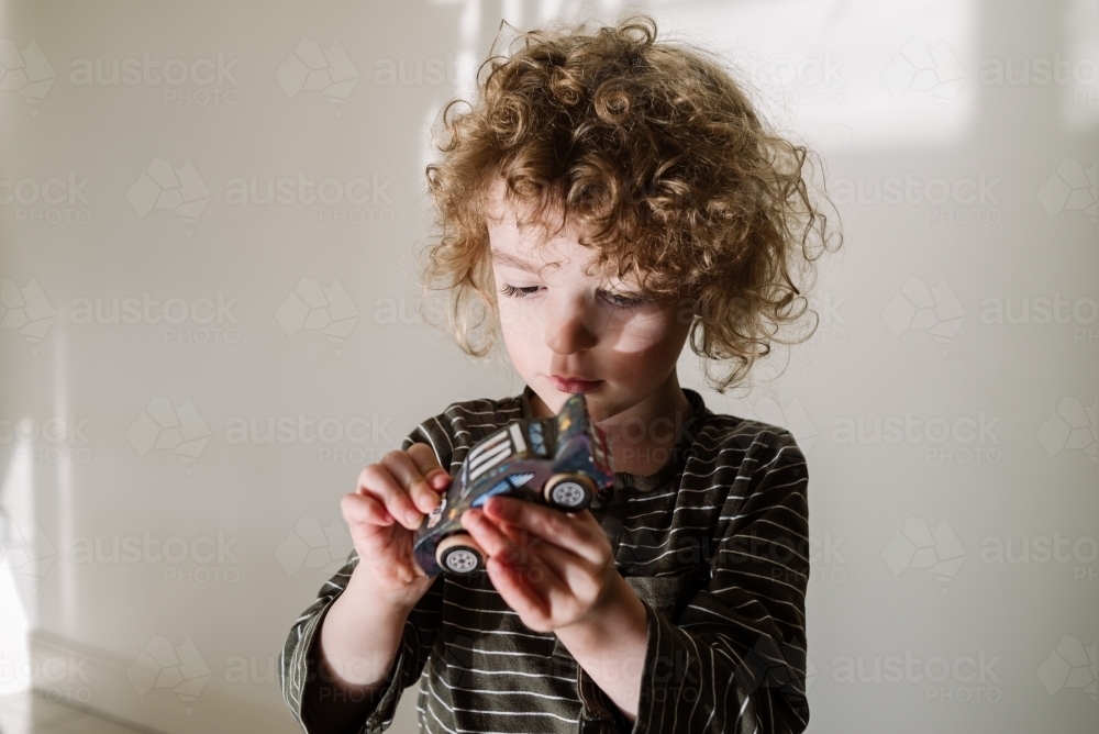 Young boy playing with a handmade model kit wooden toy car - Australian Stock Image