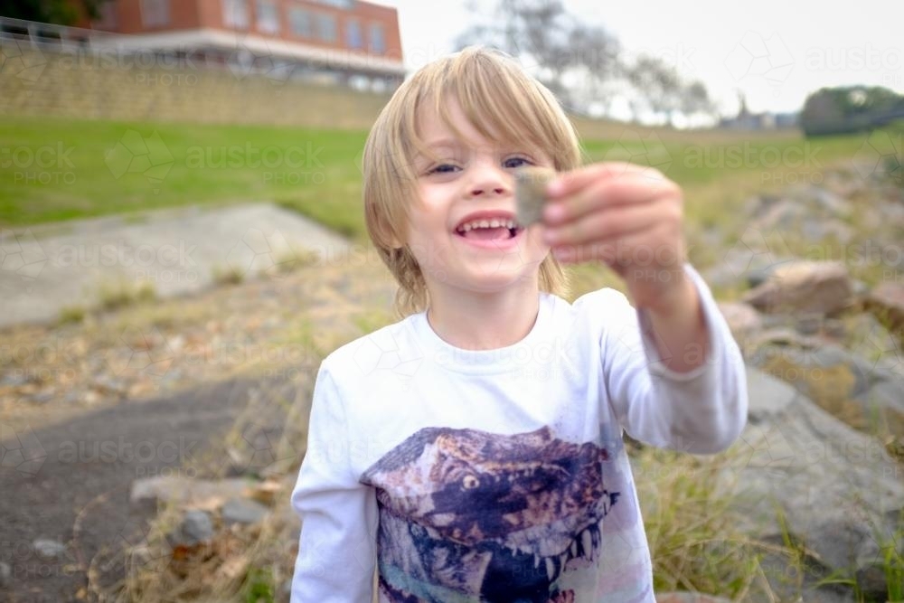 Young boy playing with rocks by the water - Australian Stock Image