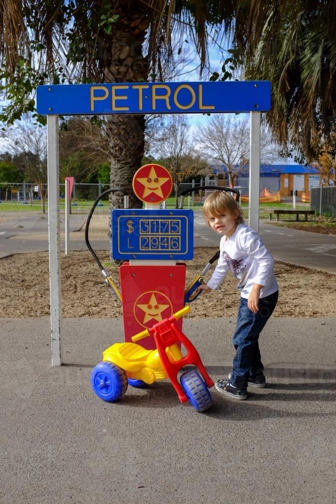 Young boy playing with toy bike pretending to fill with petrol - Australian Stock Image