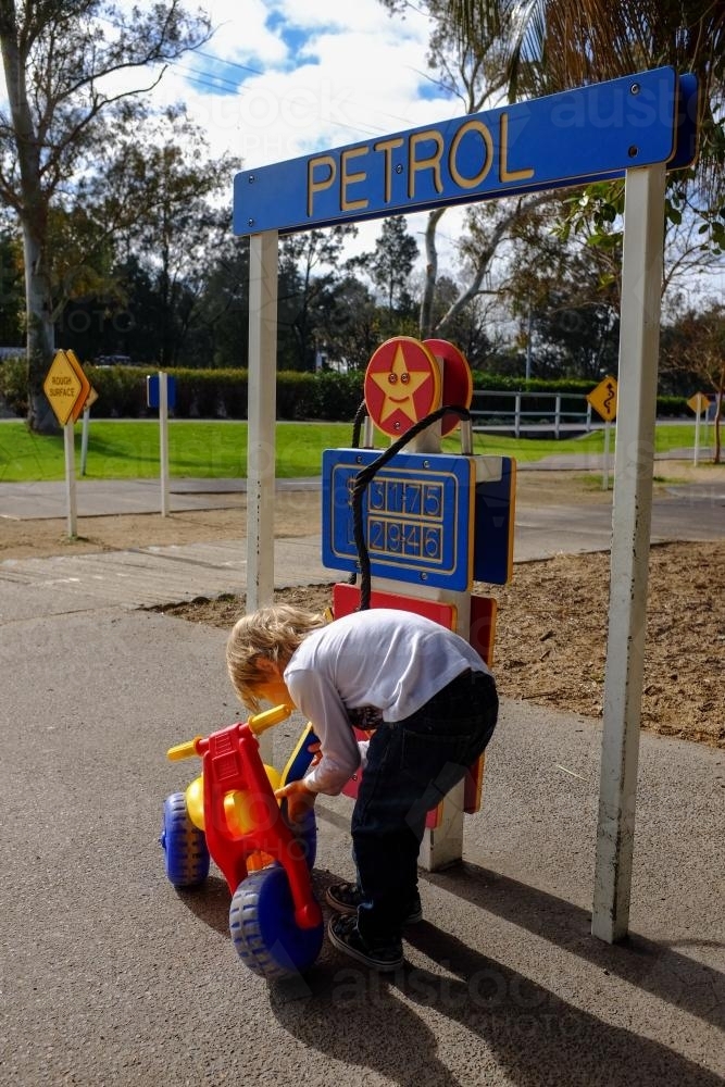 Young boy playing with toy bike pretending to fill with petrol - Australian Stock Image