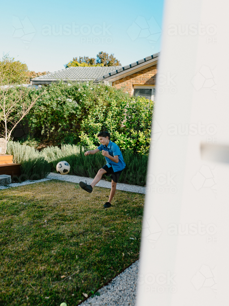 Young boy practicing soccer in backyard - Australian Stock Image