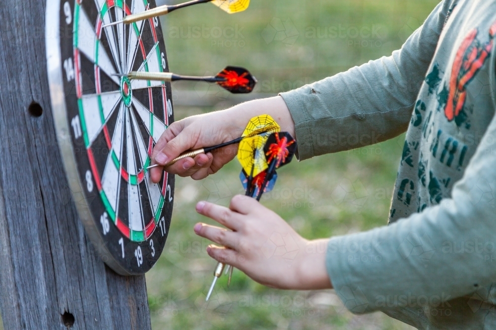 Image of Young boy pulling throwing darts of game board Austockphoto