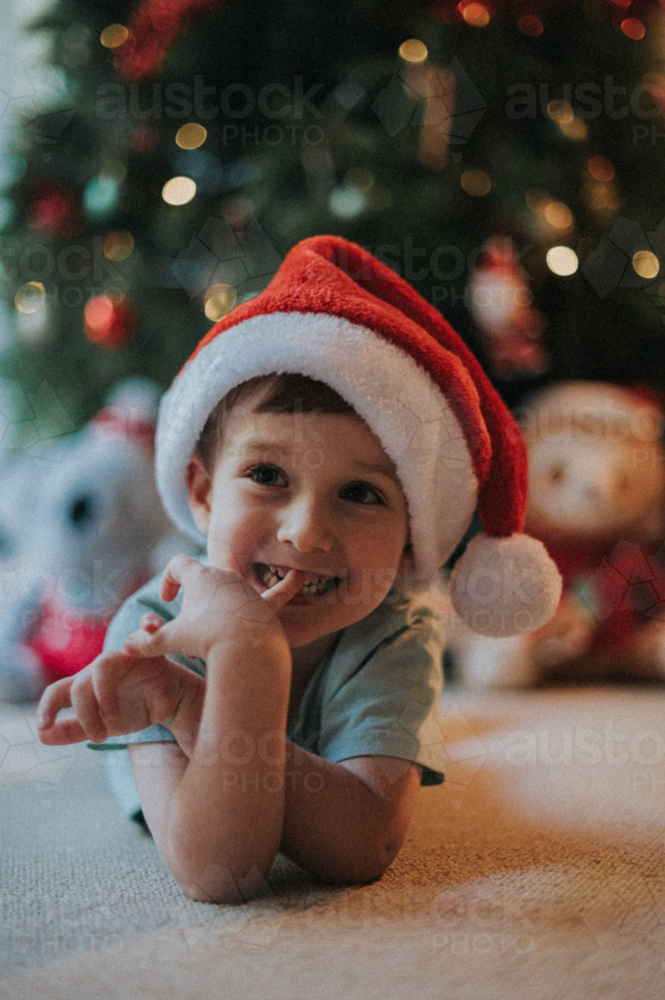 young boy radiates happiness in his Christmas hat - Australian Stock Image