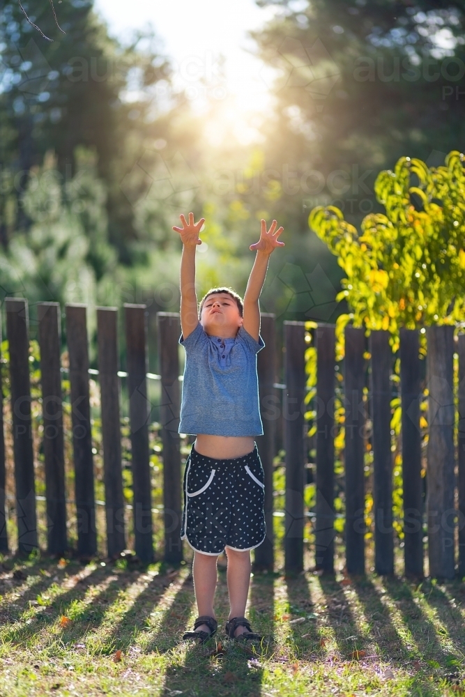 Young boy reaching up to grab the sunshine - Australian Stock Image