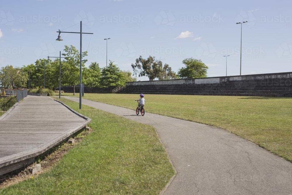 Young boy riding bike along bike path - Australian Stock Image