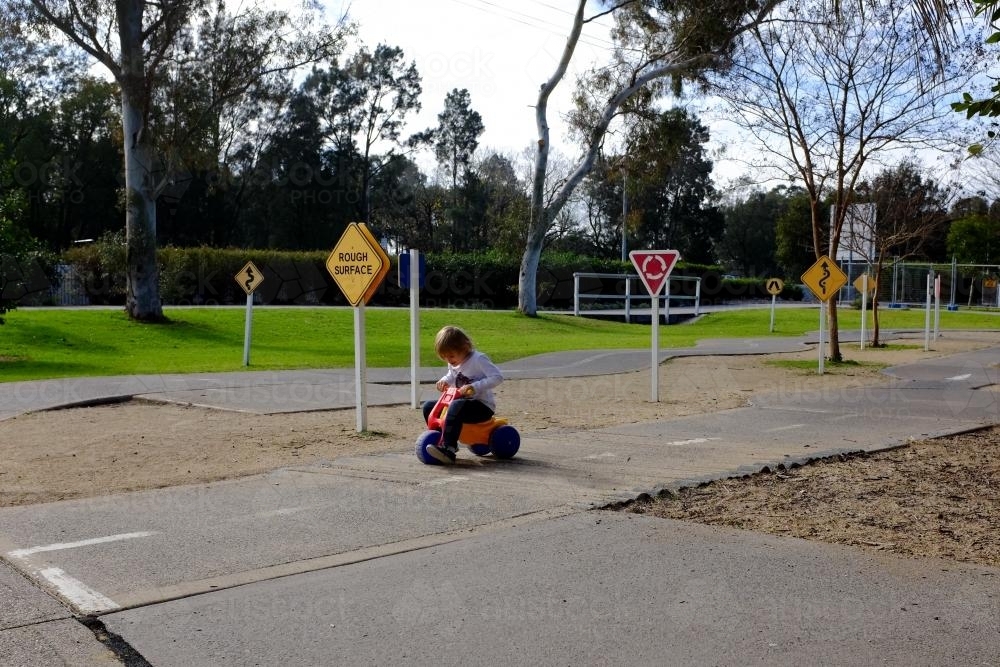 Young Boy riding bike around children's playground - Australian Stock Image