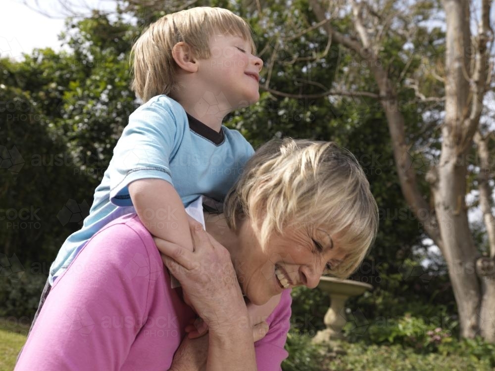 Young boy riding on shoulders of older woman - Australian Stock Image